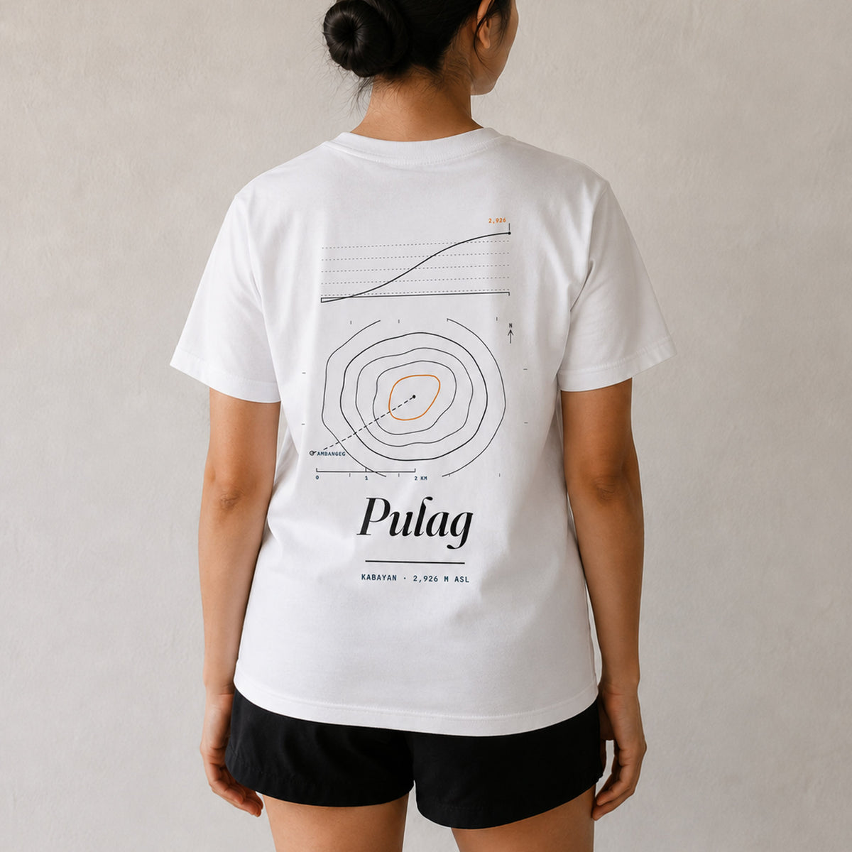 Woman seen from behind in the white Pulag tee, summit contour map and elevation profile printed across her back