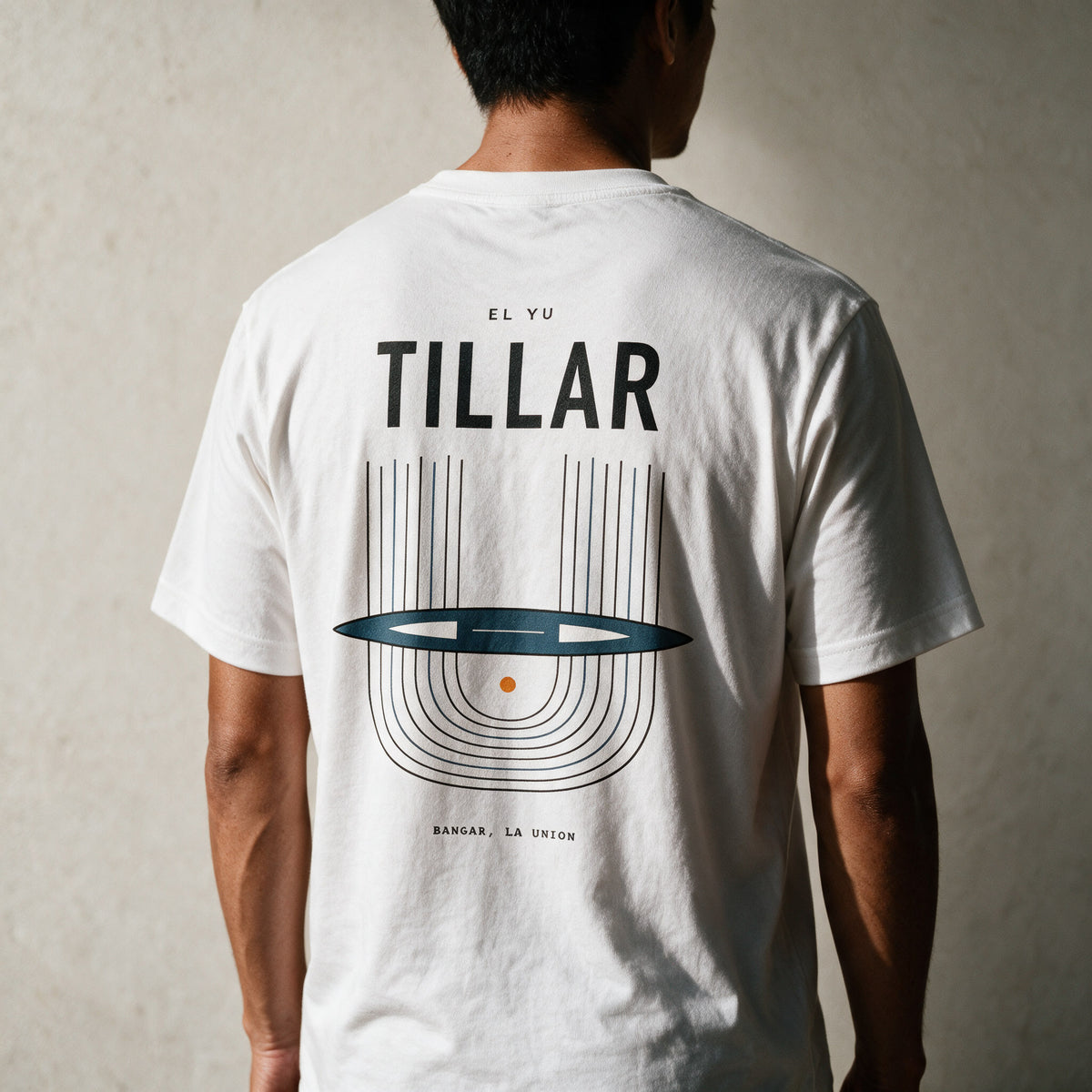 Man in the white Tillar tee, back view, TILLAR over the Ilocano handloom print