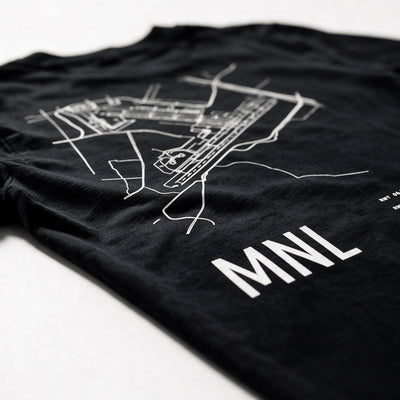 Airport Series MNL tee folded on white, close on the printed Ninoy Aquino runway map and the MNL code
