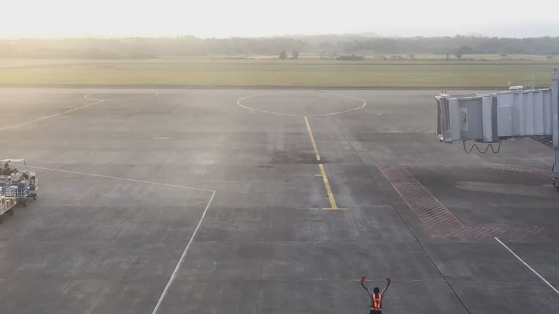Aircraft arriving at a gate at Iloilo International Airport at sunset, ground crew marshalling it in