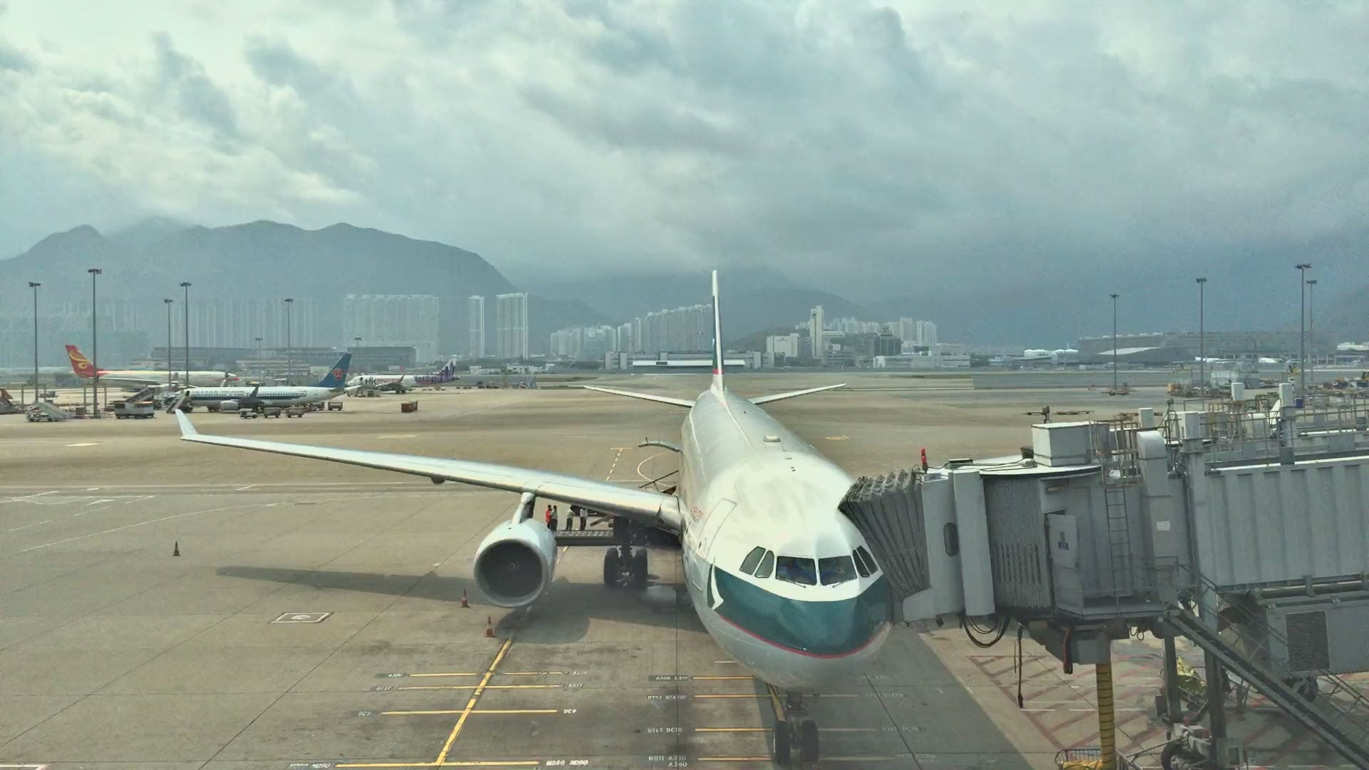 Load video: Cathay Pacific aircraft at a Hong Kong International Airport gate, Lantau hills behind