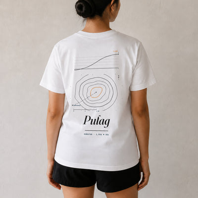 Woman seen from behind in the white Pulag tee, summit contour map and elevation profile printed across her back