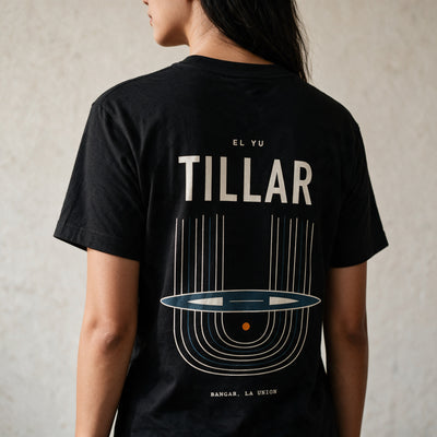 Woman in the Midnight Black Tillar tee, back view, TILLAR over the handloom print in cream and blue